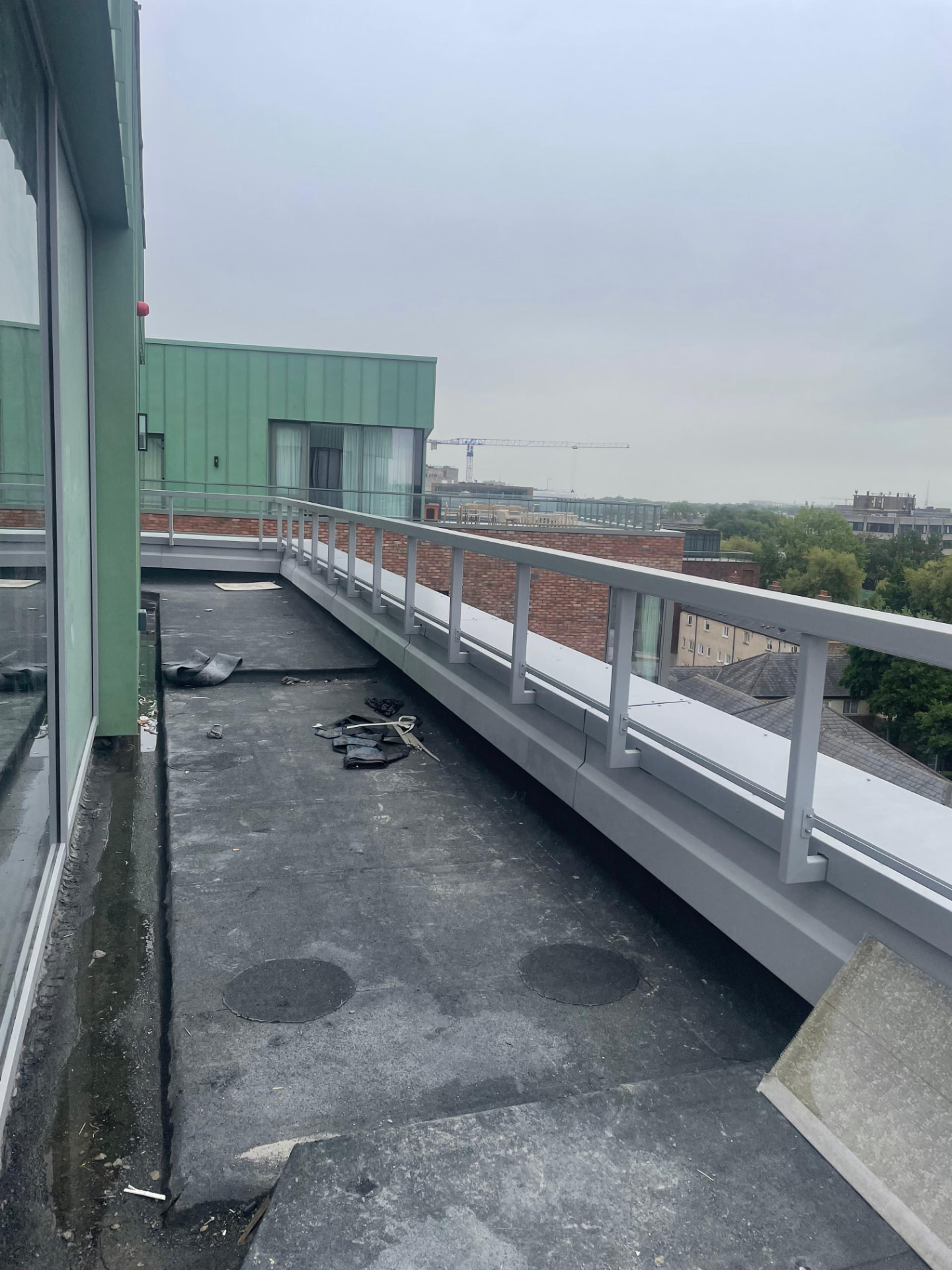 Roof terrace balustrade seen from the far end with rooftops and cranes in the distance