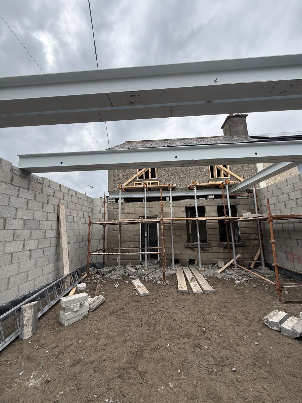 Painted steel beams spanning the blockwork walls of a rear extension in front of an existing house