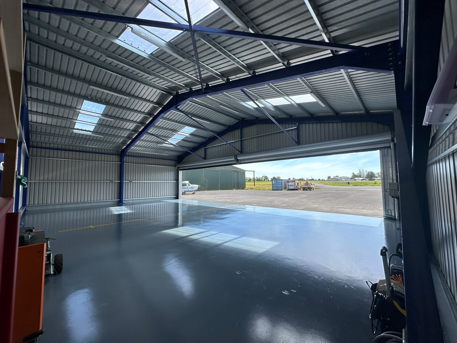 Inside a completed steel framed hangar with painted portal frame, rooflights and a full width roller door