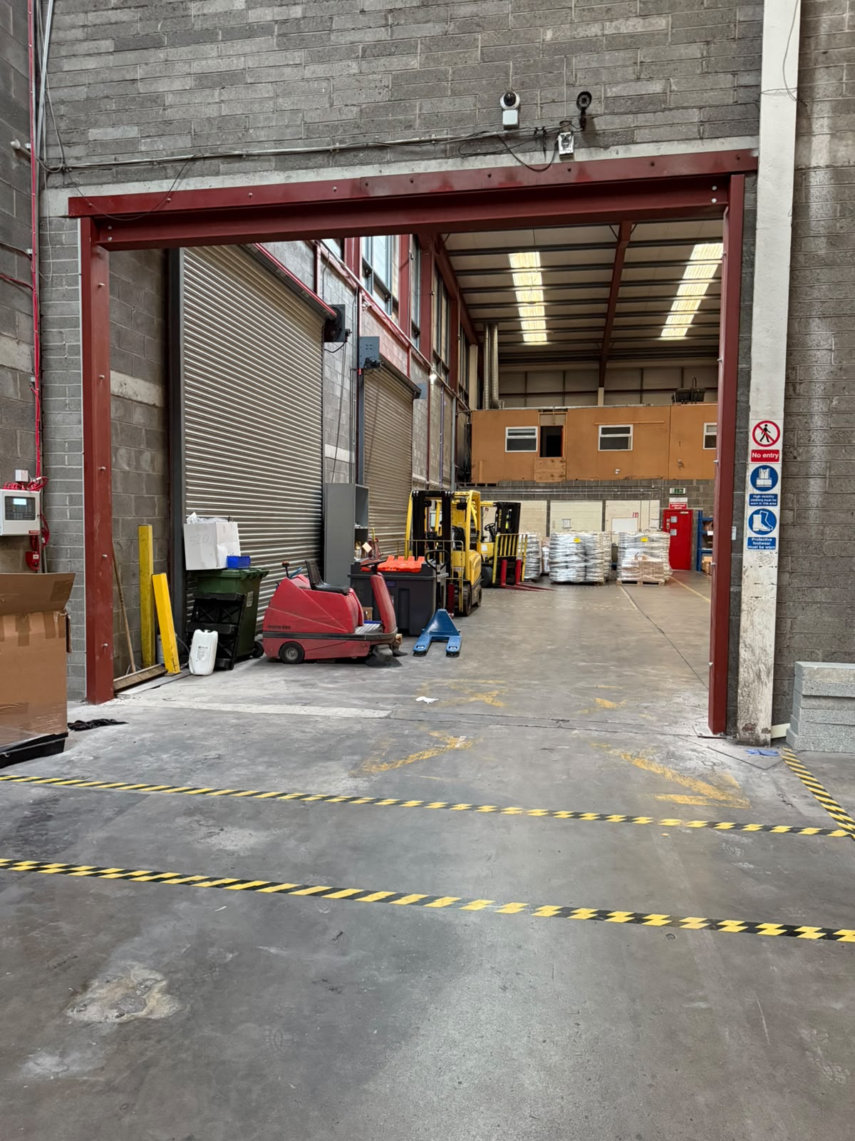 Red painted steel goal post frame forming a new door opening in a warehouse block wall