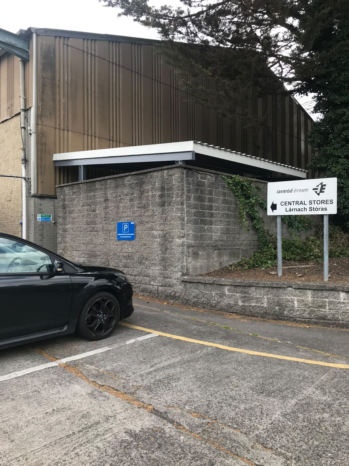 Steel canopy with white fascia fixed over a blockwork store beside an industrial building