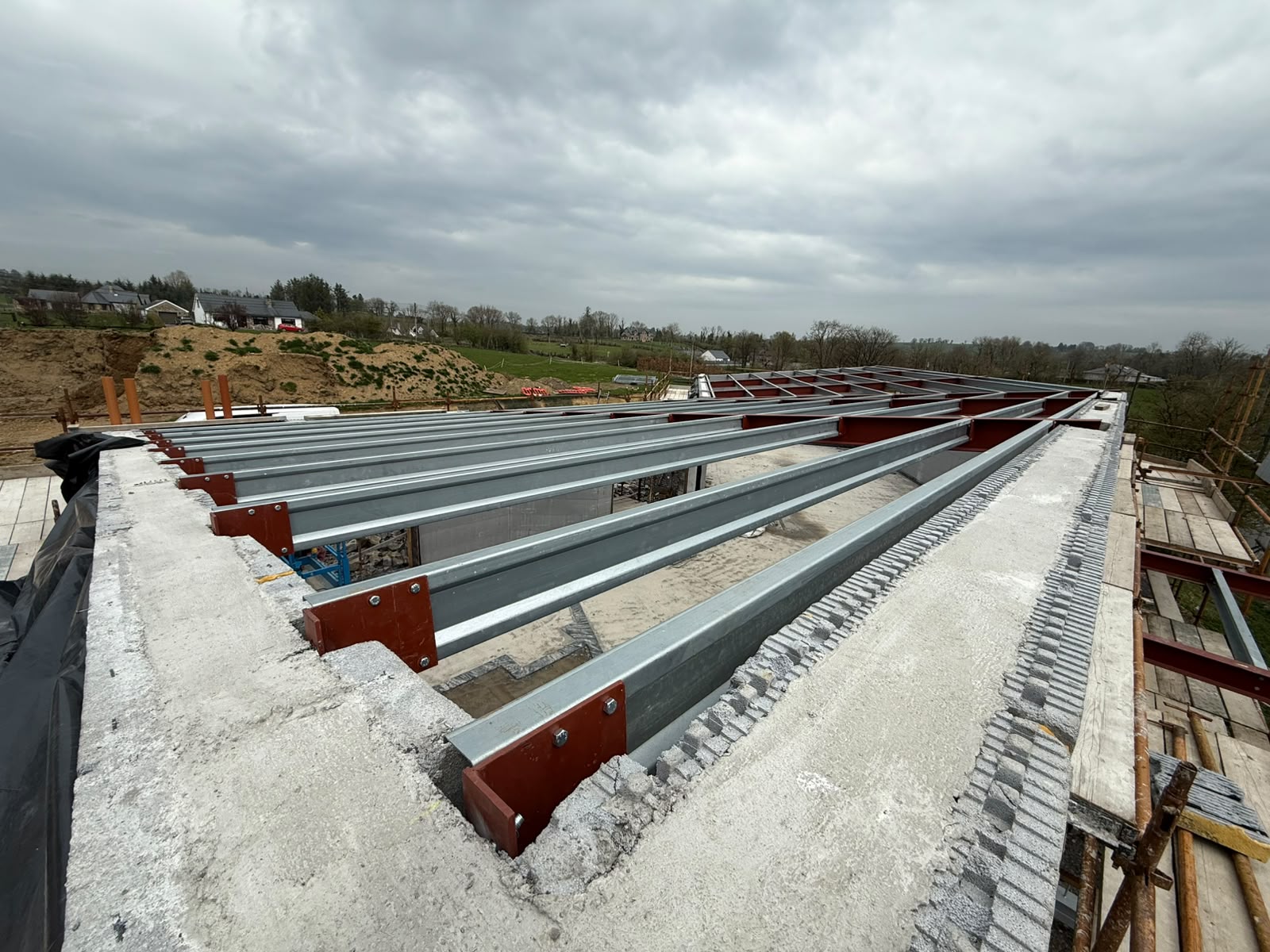 Galvanised steel floor beams bolted onto red painted supports over blockwork walls on a new build house