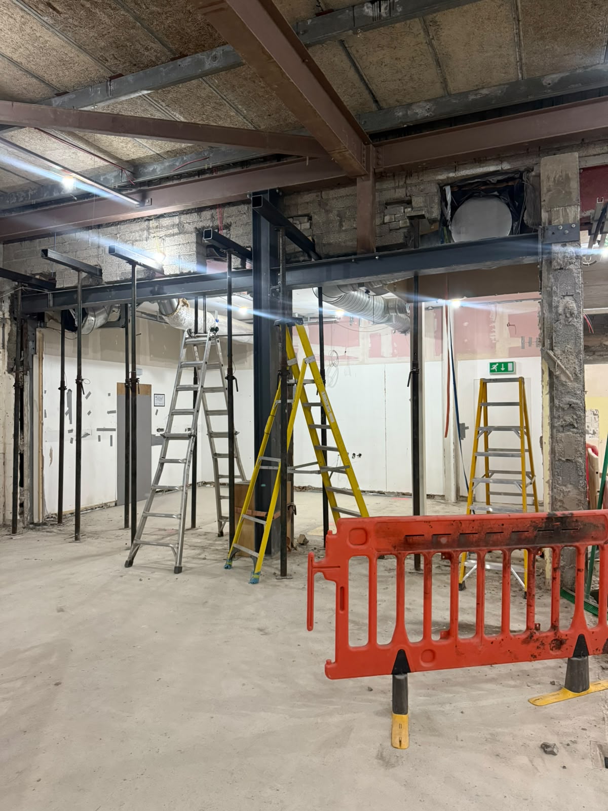 Steel beams and columns installed on adjustable props inside a stripped out retail unit