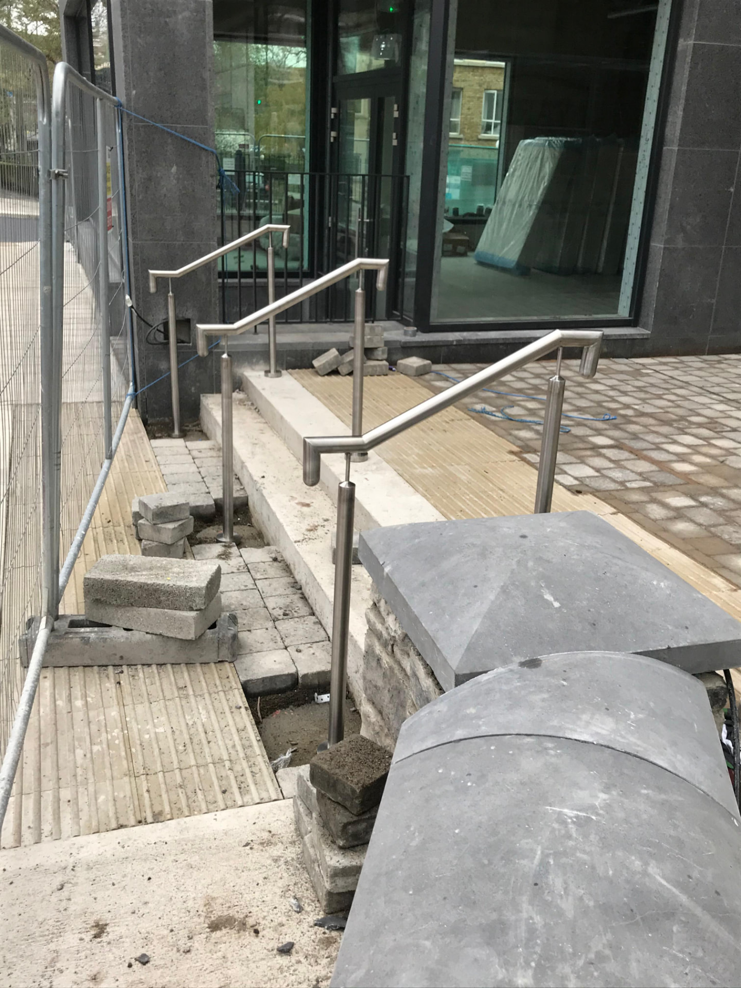 Brushed stainless steel handrails with curved returns to external granite entrance steps of an apartment building