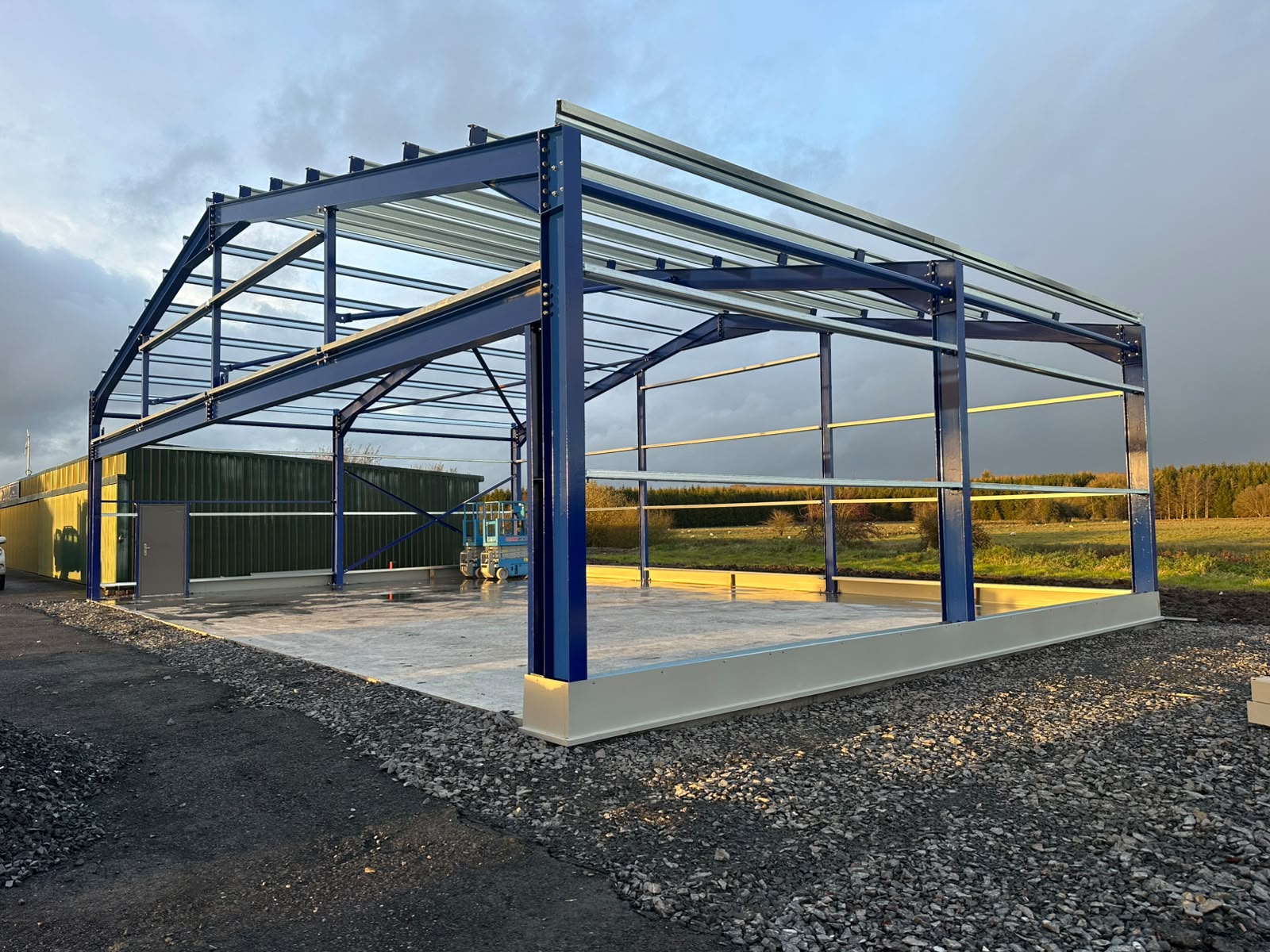Blue painted steel portal frame shed erected with purlins, side rails and cladding rails in place