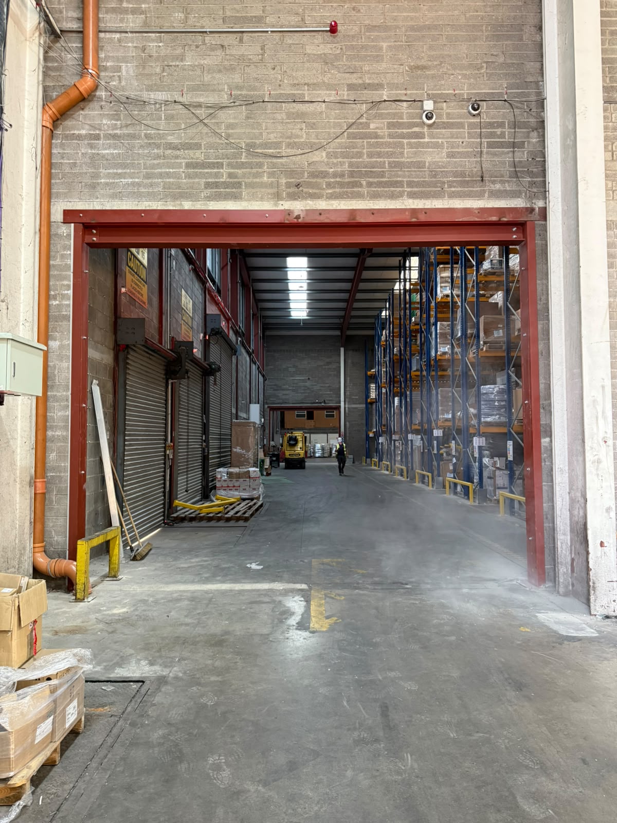Second steel framed opening looking through to warehouse racking and a forklift