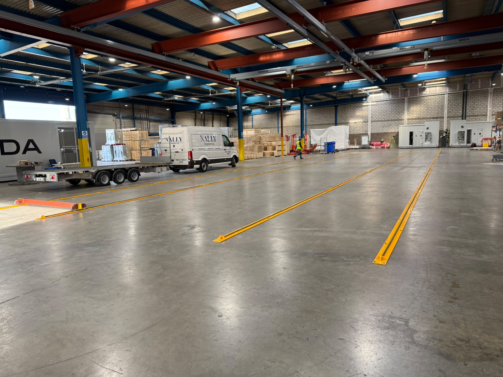 Nally Engineering van and trailer beside newly installed yellow floor rails in a large production hall