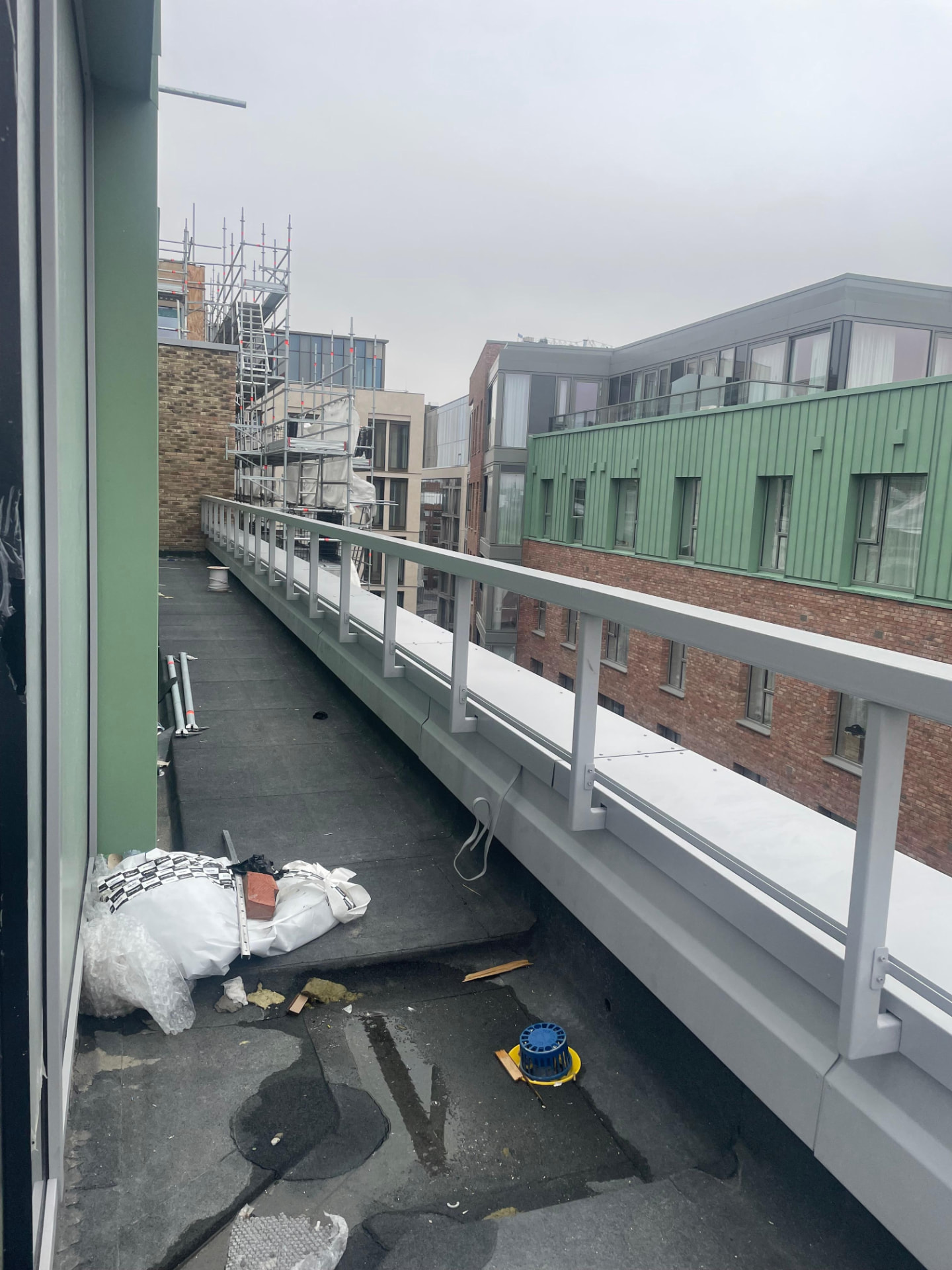 Long grey steel balustrade with posts and rails running along the edge of a roof terrace
