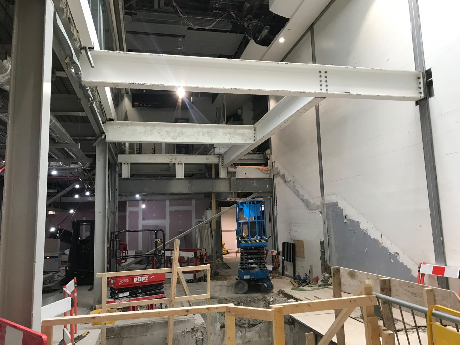 White painted steel beams and columns installed through the double height area of a retail unit under fit-out