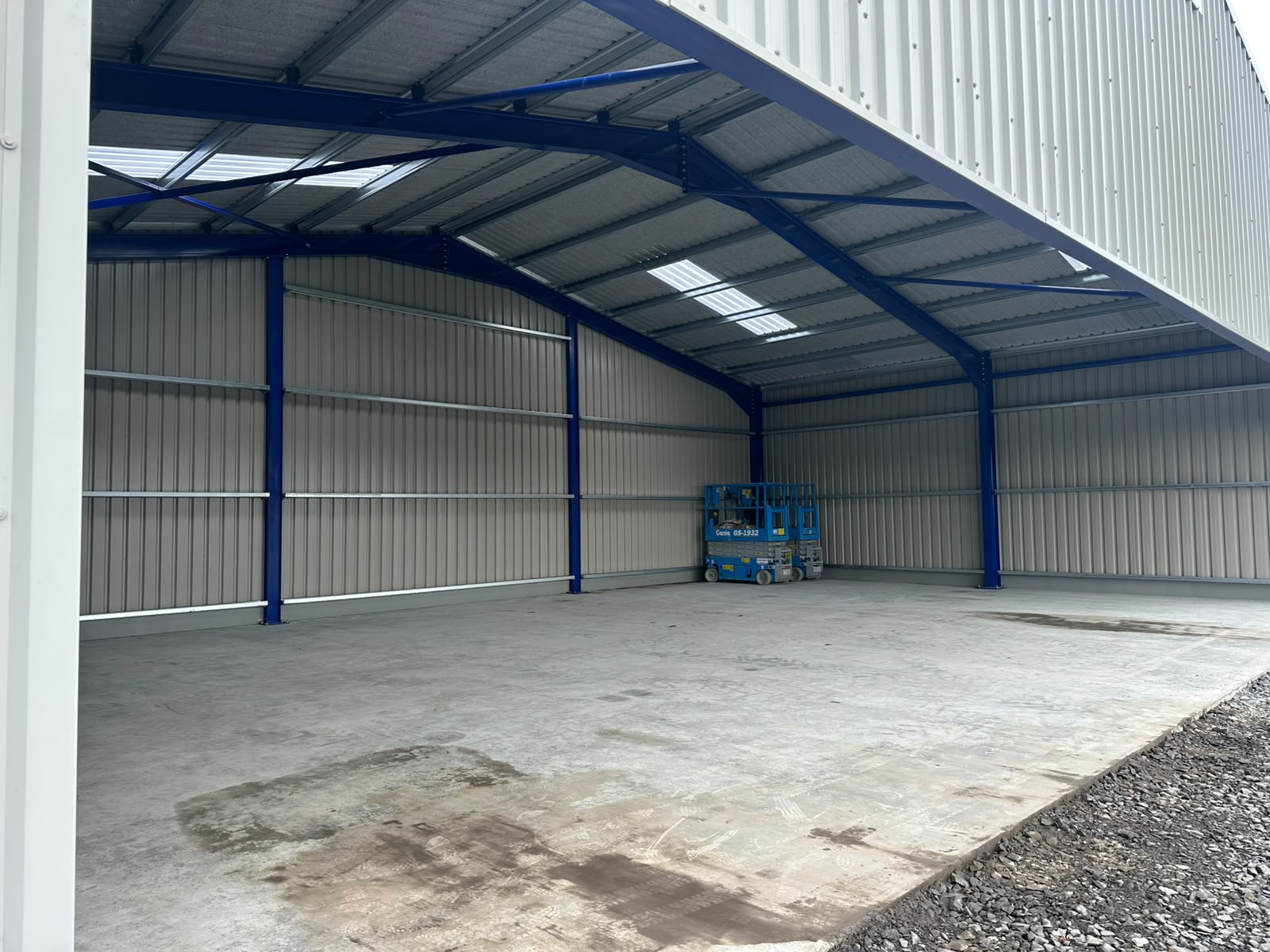 Interior of a completed hangar with blue painted portal frame, insulated sheeting, side rails and rooflights