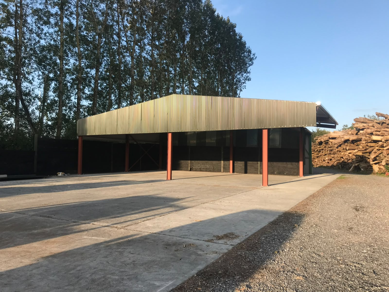 Completed agricultural lean-to canopy with red painted columns and galvanised sheeting over a concrete yard